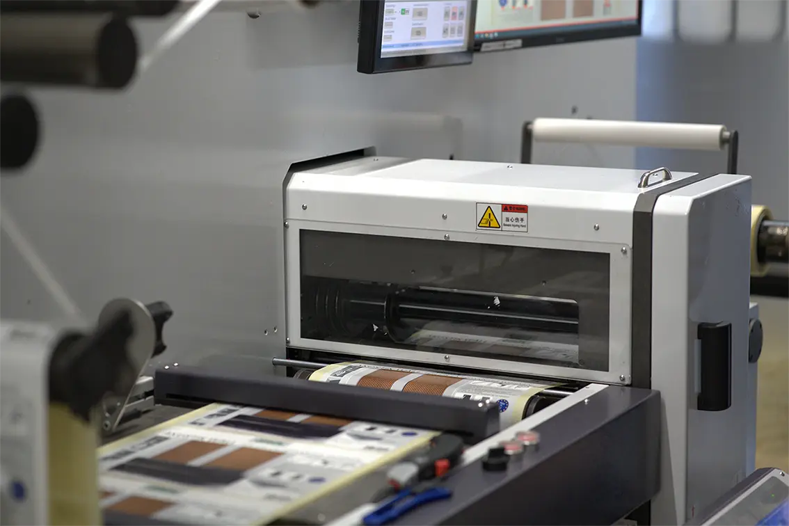 Industrielle Druckmaschine verarbeitet bedruckte Etiketten auf einer Produktionslinie.